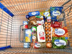 a shopping cart filled with food and condiments on top of a wooden floor