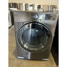 a washing machine with the door open in a room full of washers and dryers