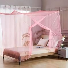 a pink canopy bed in a bedroom with white walls and wooden floors, along with curtains