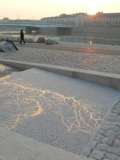 a skateboarder is riding his board on the sidewalk near some rocks and water