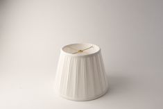 a white lamp shade with a gold ring on the top and bottom, against a white background