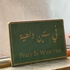 there is a sign that says peace be with you in two languages on the window sill