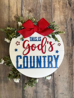 this god's country ornament with red bow on it is hanging on a wooden wall