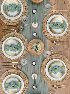 a wooden table topped with white plates and silverware