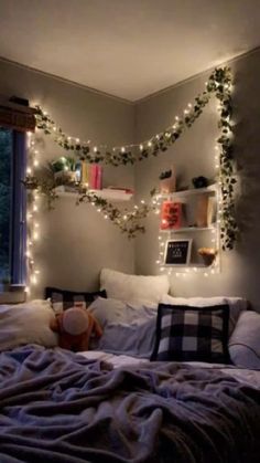 an unmade bed with christmas lights on the headboard