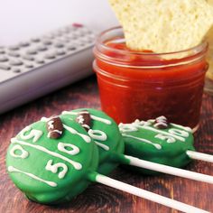 two green cookies with white frosting on them next to a jar of ketchup