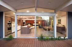 an open kitchen and living room are seen through the sliding glass doors on this modern home