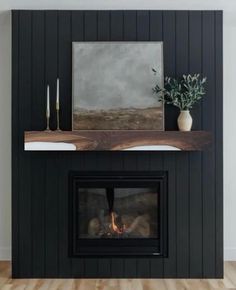 a fireplace with a painting on the mantle and a potted plant next to it