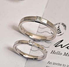 two wedding rings sitting on top of a piece of paper next to each other,