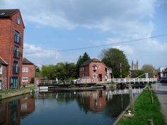 a river running through a small town next to tall brick buildings on the side of a road