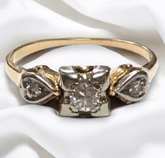 an old diamond ring is sitting on a white cloth