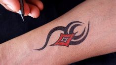 a person with a tattoo on their arm holding a pen and pointing at the camera