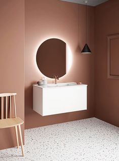 a white sink sitting under a round mirror in a bathroom next to a wooden chair