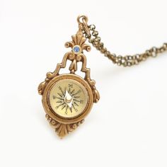 an antique style compass necklace on a white background