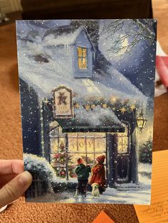 a person holding up a card with a christmas scene on it