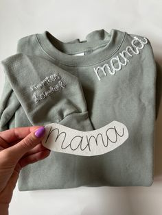 a person holding up a shirt with the word mama on it