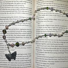 an open book with two bracelets on it and a butterfly charm in the middle