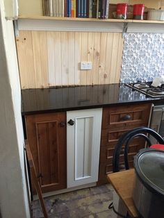 a kitchen with wooden cabinets and tile flooring in the middle, along with bookshelves