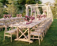 a long table set up with chairs and flowers in vases on the tables for an outdoor wedding reception