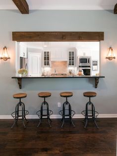 a kitchen with four stools in front of the counter