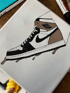 a painting of a pair of shoes on top of a piece of paper next to markers and pens