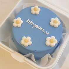 a blue cake with white flowers on it in a plastic container that says hygonu