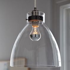 a clear light fixture hanging from a ceiling in a room with white walls and windows