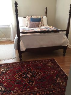 a bed sitting on top of a wooden floor next to a rug