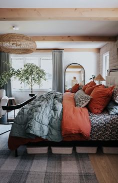 a large bed with many pillows and blankets on top of it in a room next to a window