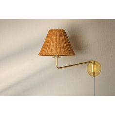 a wall light with a woven shade on it's side next to a white wall