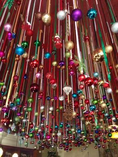 a room filled with lots of colorful christmas ornaments hanging from the ceiling and lights on the ceiling