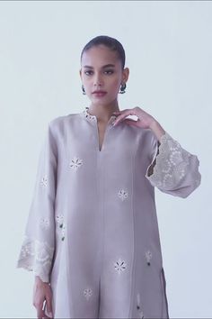 A beautifully crafted silver rawsilk fabric with floral eyelet detailing and embroidered sleeves. The look is completed with matching co-ord izaar with embroidered hem. Elegant Chikankari Embroidered Top For Summer, Elegant Summer Chikankari Embroidered Top, Elegant Summer Top With Chikankari Embroidery, Elegant Chikankari Embroidered Top For Wedding, Elegant Blouse With Intricate Embroidery For Eid, Elegant Eid Blouse With Intricate Embroidery, Elegant Embroidered Top With Sleeves For Summer, Intricate Embroidery Top For Wedding, Intricate Embroidery Embroidered Top For Wedding