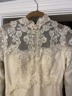 the back of a wedding dress on a hanger in front of a white window