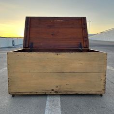 an old wooden box sitting in the middle of a parking lot at sunset or sunrise