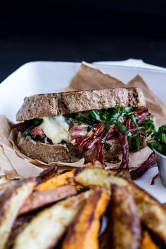 a sandwich and some fries on a white plate with paper wrappers next to it