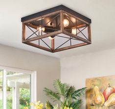 a light fixture hanging from the ceiling in a room with flowers and paintings on the wall