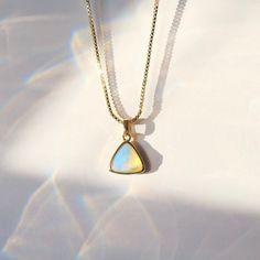 C R Y S T A L ∙ P E N D A N T ∙ N E C K L A C E Embrace the ethereal beauty of the opal with this dainty pendant necklace, whispering a touch of magic into your everyday. This captivating gemstone shimmers with flashes of rainbow fire, capturing the ever-changing essence of moonlight and dreams. Opal is beautiful blueish white stone is known for it's ability to encourage: Inspiration, Creativity, and Emotional Healing. * Design: Triangle Crystal Pendant - Box Chain Necklace & Beaded Necklace * Material & Finish: 18K Gold Plated Brass * Pendant: Faceted Triangle Shape * Pendant Size (Approx.): 10 x 10 mm | 0.375 x 0.375 in * Necklace Length - 3 Options: 16in, 18in, 20in ** Your necklace may vary slightly due to the uniqueness of the stone B I R TH S T O N E ∙ A N D ∙ Z O D I A C * Birthston Gold Clavicle Chain Necklace With Moonstone, Gift Moonstone Necklace With Adjustable Chain, Gold Moonstone Necklace As Gift, Gold Moonstone Necklace For Gift, White Dainty Jewelry With Box Chain, Spiritual Box Chain Necklace As Gift, Spiritual Box Chain Necklace Gift, White Dainty Box Chain Necklace, Brass Gemstone Necklace For Gift