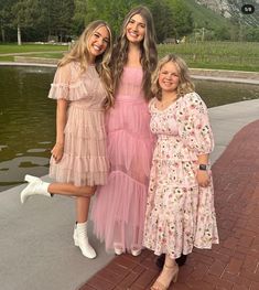 three women standing next to each other near water