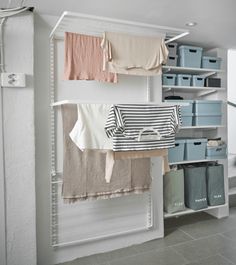 an organized closet with clothes hanging from the ceiling and storage bins on the wall