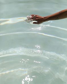 a person's hand reaching for something in the clear blue water that they are holding