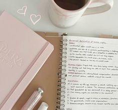 an open notebook with writing on it next to a cup of coffee