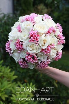 a bouquet of white and pink flowers in someone's hand