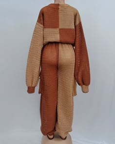 a mannequin wearing a brown and tan knitted outfit with long sleeves, standing on a white surface