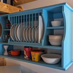 a blue shelf filled with plates and bowls next to a wall mounted rack holding dishes