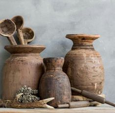 three vases with wooden spoons and other items on a table next to each other