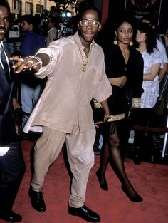 a man in a suit and tie standing on a red carpet next to other people