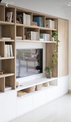 a living room with bookshelves and a television on top of the entertainment center