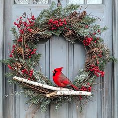 a red cardinal sitting on top of a wooden branch next to a wreath filled with berries and pine cones