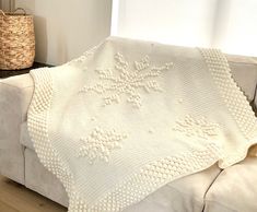 a white crocheted blanket sitting on top of a couch