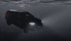 a car underwater in the ocean with its headlights on